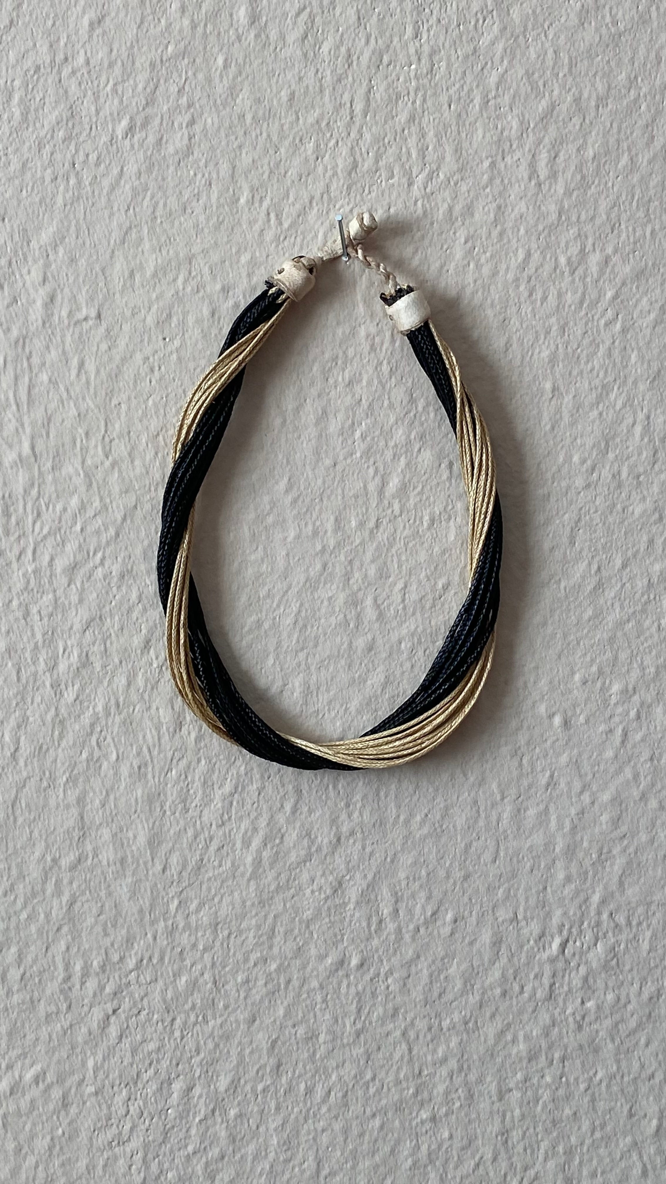 Goro Halskette von ABENIN – handgefertigt in Benin aus geflochtenem Gras in Schwarz und Naturtönen. Die gedrehte Optik macht das nachhaltige Design besonders elegant und modern.