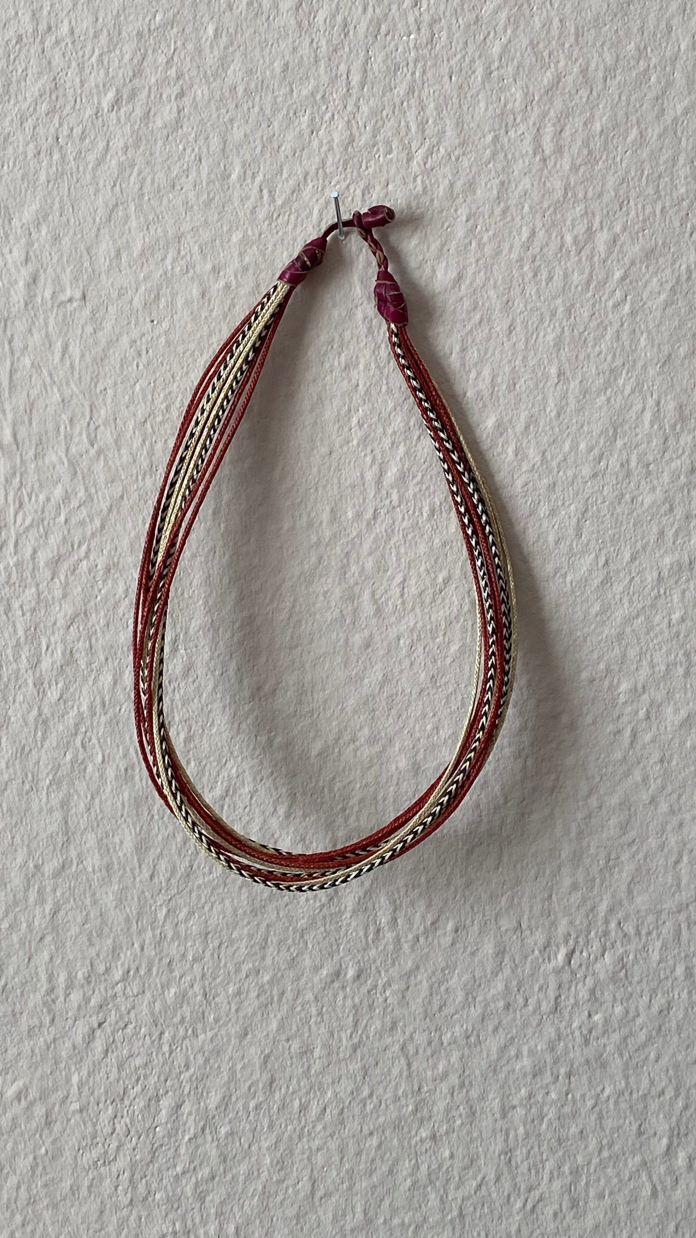 Moumi Halskette von ABENIN – handgefertigter Schmuck aus geflochtenem Gras in Natur-, Rot- und Schwarztönen mit Lederabschluss. Ausdrucksstarker Fair Trade Schmuck aus Benin – kunstvoll, nachhaltig, voller Seele.