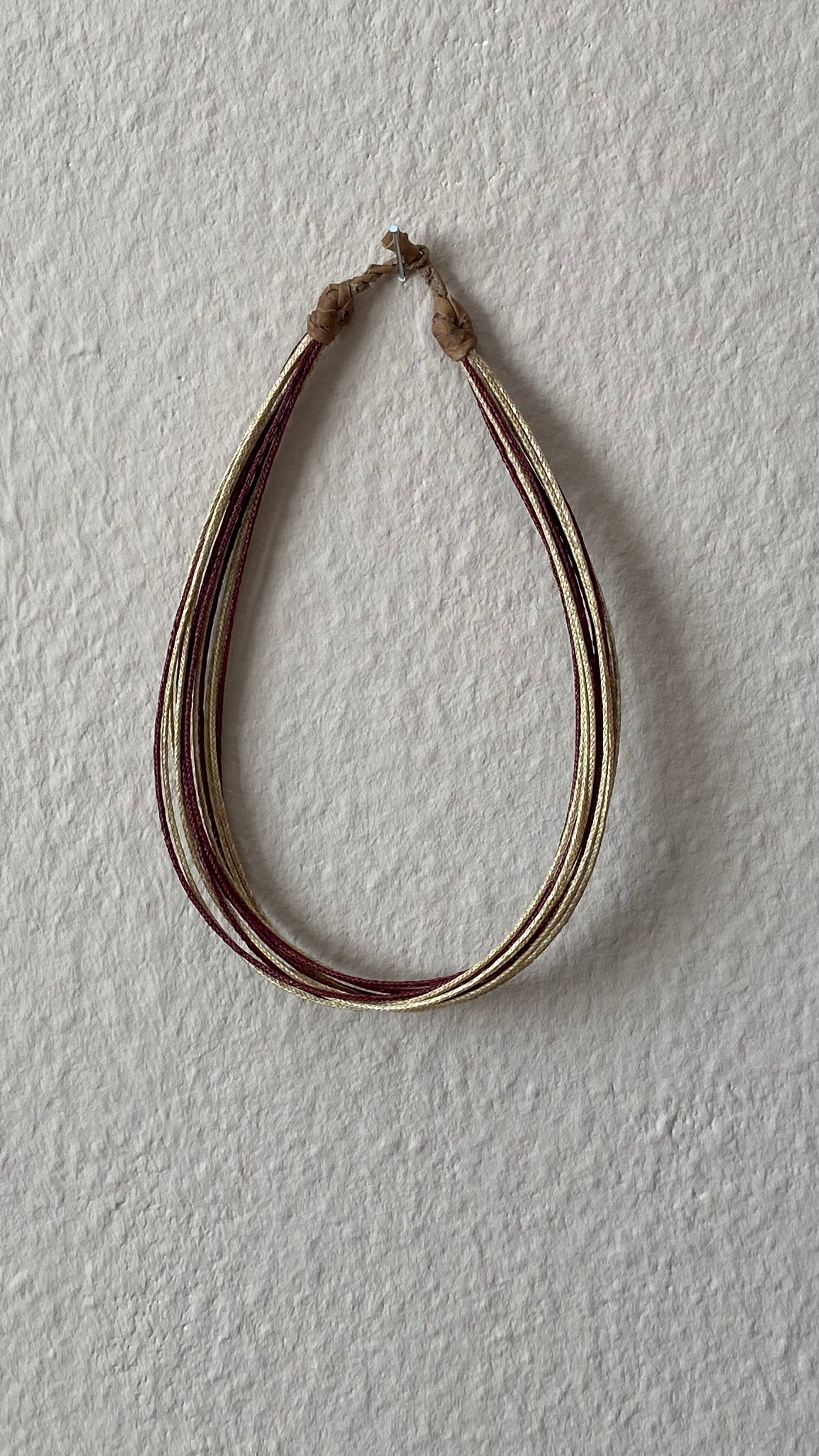 Moumi Halskette von ABENIN – handgefertigter Schmuck aus geflochtenem Gras in Natur- und Rot mit hellem Lederabschluss. Nachhaltige Halskette aus Benin – filigran, fair, stilvoll.