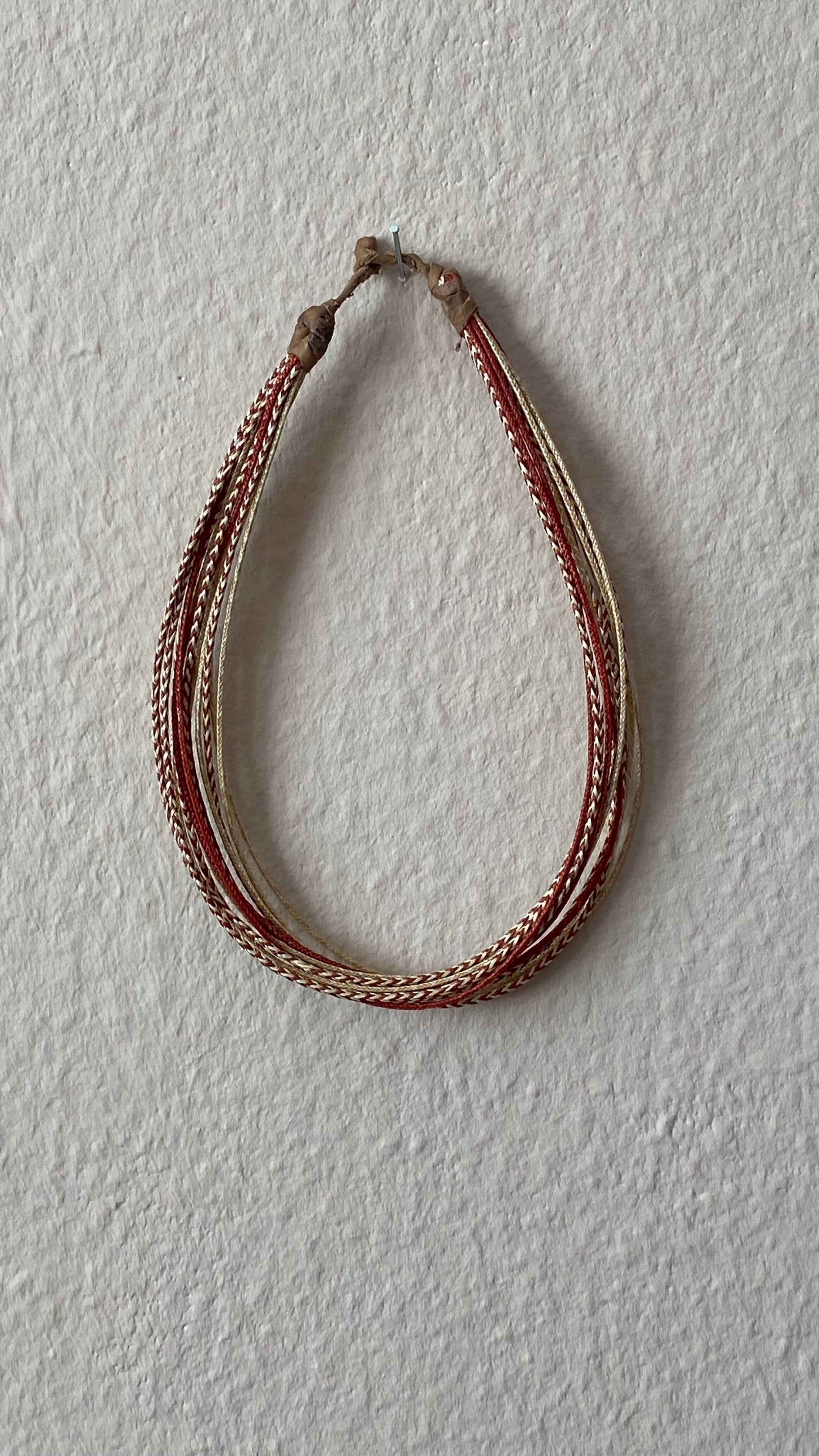 Moumi Halskette von ABENIN – filigran geflochtene Halskette aus natur- und rot gefärbtem Gras mit Lederabschluss. Handgemachter, fairer Schmuck aus Benin – leicht, nachhaltig, voller Ausdruck.