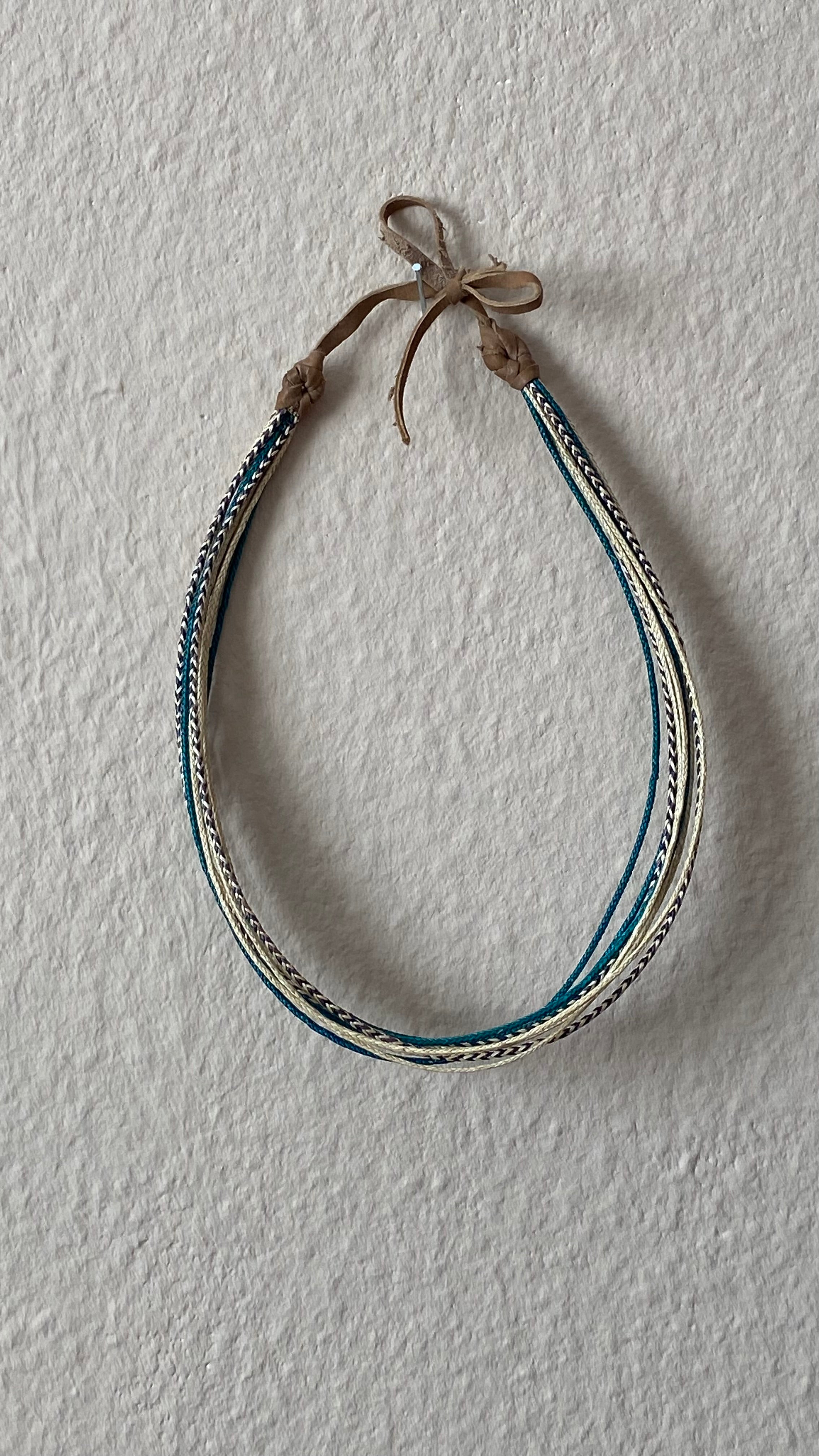 Moumi Halskette von ABENIN – fair produzierter Schmuck aus geflochtenem Gras in Türkis, Natur und Schwarz. Handgefertigt in Benin mit Lederabschluss – lebendig, nachhaltig und mit kultureller Tiefe.